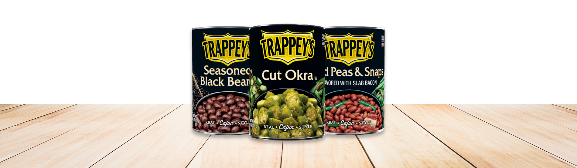 Three cans of Trappey's Canned Vegetables on a wood table